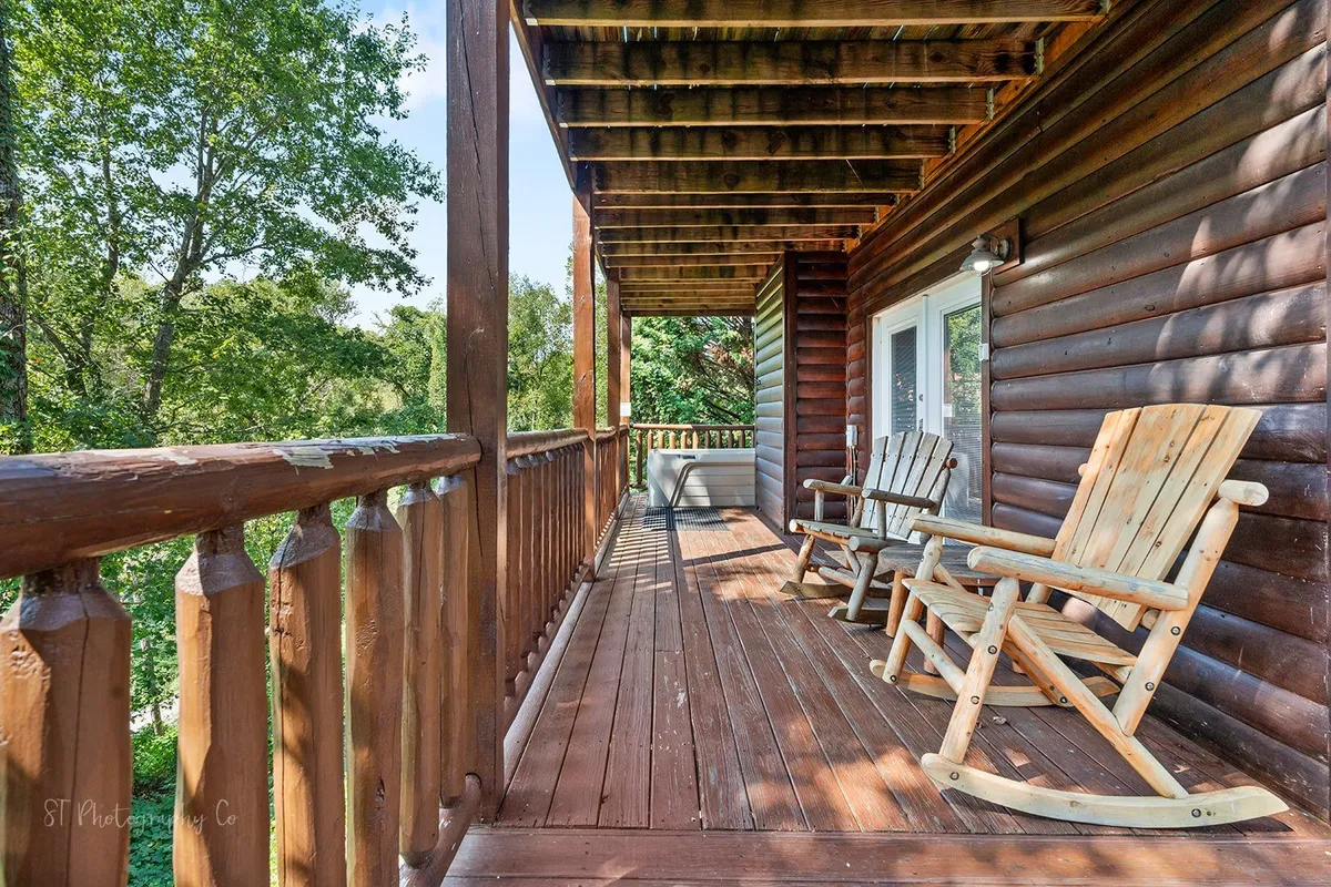 This image features classic wooden rocking chairs perched on a porch with a wooden railing overlooking dense greenery. The inviting chairs are perfect for quiet moments with a book or enjoying conversations, while the natural surroundings create a sense of seclusion and calm.