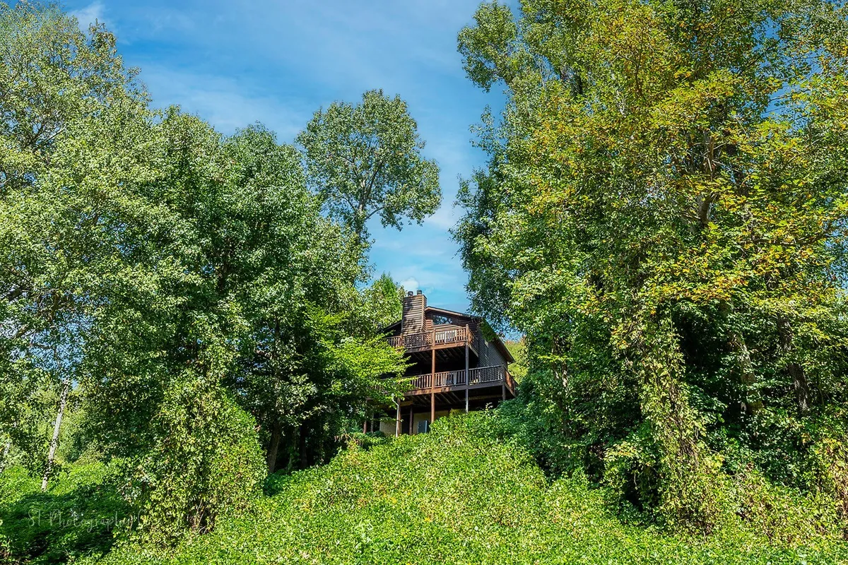 This image highlights the house nestled among lush trees, with a visible deck area that invites outdoor relaxation and gatherings. The view captures the peaceful, wooded surroundings that define the Smoky Mountain experience.